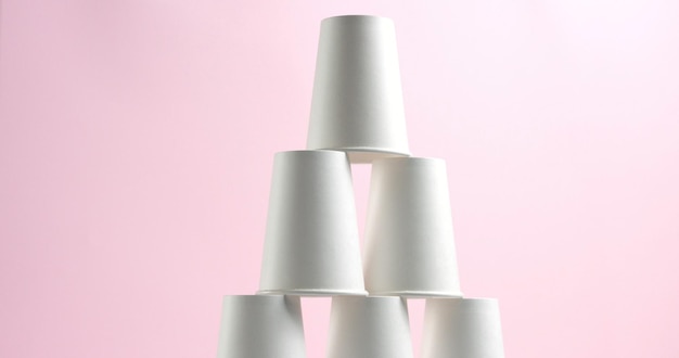 Free photo tower made of white paper cups on pink background