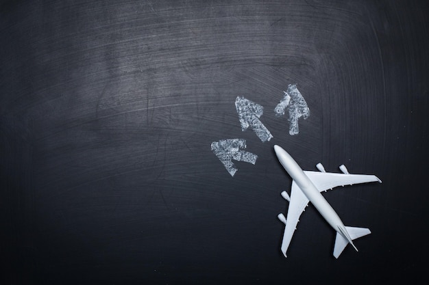 Toy airplane over chalkboard background and arrows drawings