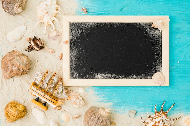 無料写真 おもちゃのボートと黒板の近くの砂の間で貝殻