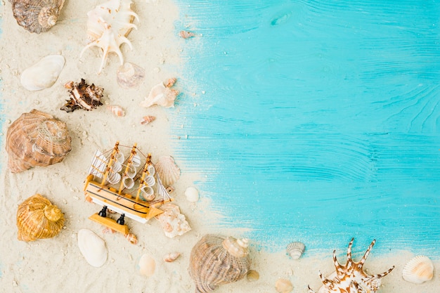 Toy boat and seashells among sand on board