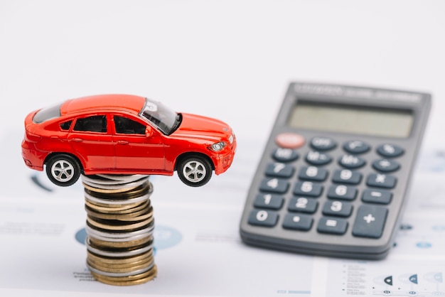 Free photo toy car over the coin stack with calculator on report