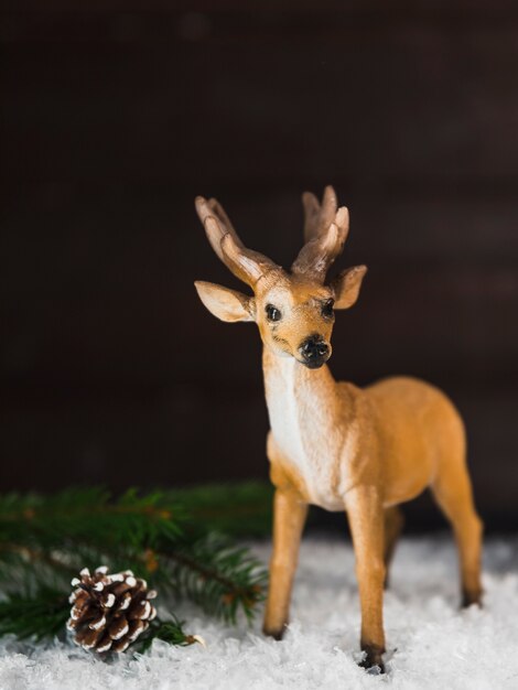 Toy deer near snag and branch on snow