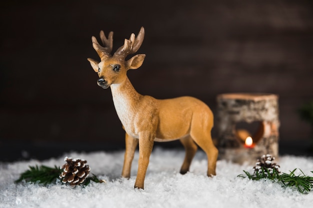 Бесплатное фото Игрушечный олень около коряг и веток на снегу