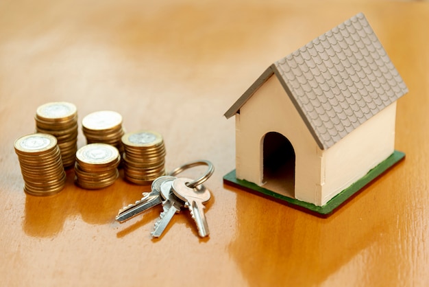 Toy model house and piles of coins front view