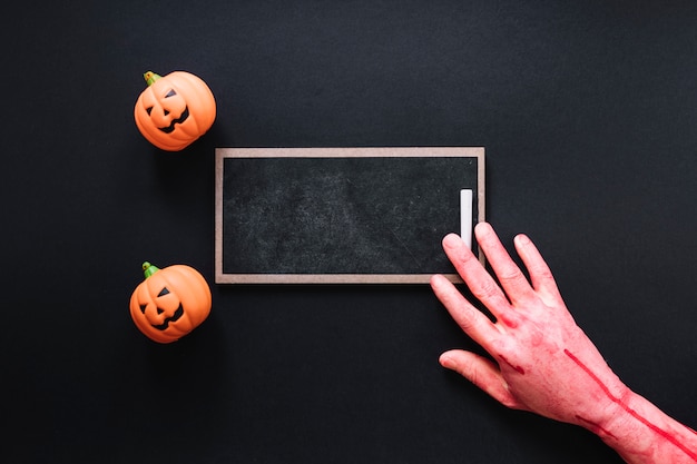 Free photo toy pumpkins with chalkboard and pink hand