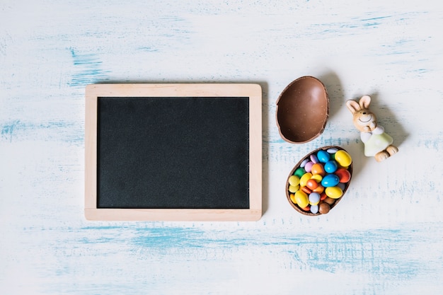 Foto gratuita coniglio del giocattolo e uovo di cioccolato vicino alla lavagna