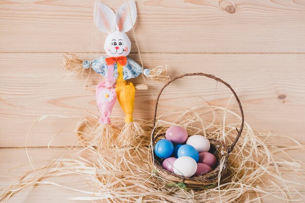 卵付きバスケットの近くにおもちゃのウサギ