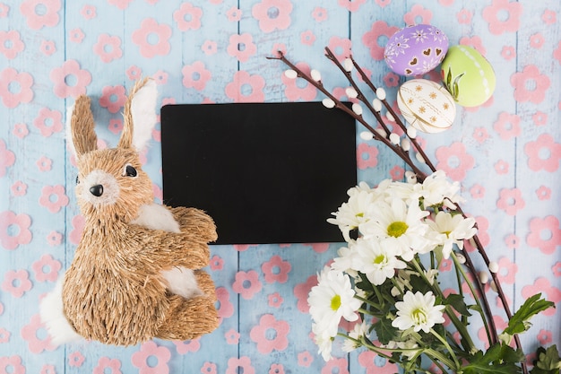 Игрушечный кролик возле бумаги и пасхальные символы