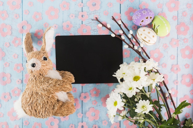 Toy rabbit near paper and Easter symbols