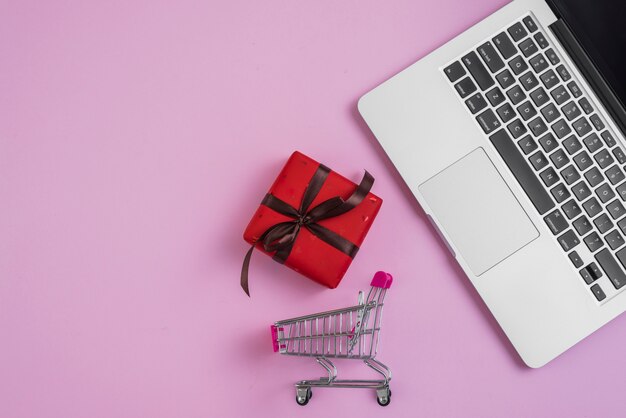 Toy shopping trolley and present near laptop keyboard