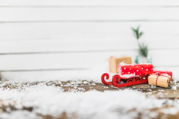 Бесплатное фото Игрушечные сани возле подарочных коробок между снежинками