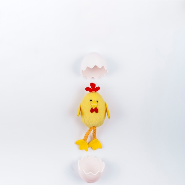Foto gratuita giochi il piccolo pollo con le coperture dell'uovo sulla tavola bianca
