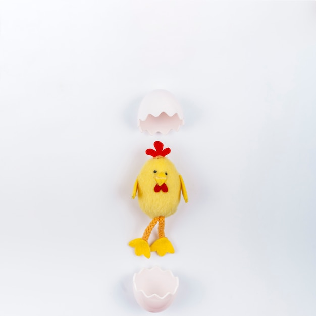 Игрушка маленькая курица с яичной скорлупой на белом столе
