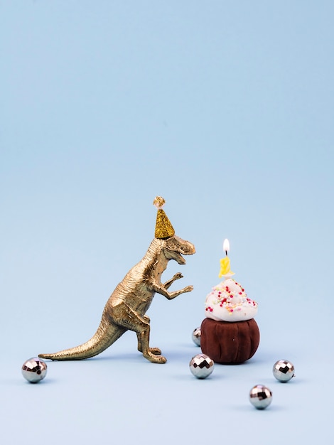 Free photo toy t-rex and little birthday dessert