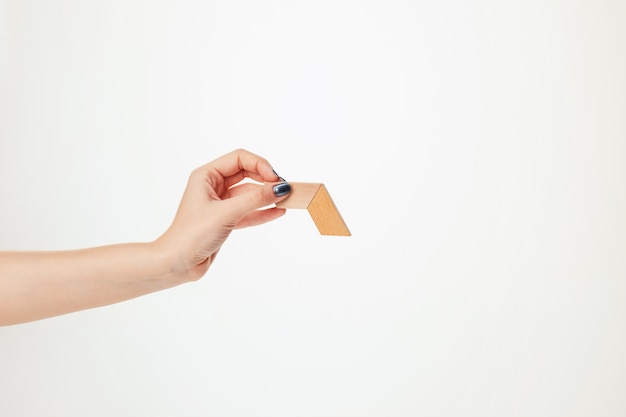 The toy wooden puzzle in hand isolated on white wall