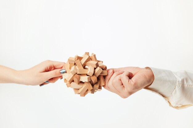 The toy wooden puzzle in hands isolated on white background