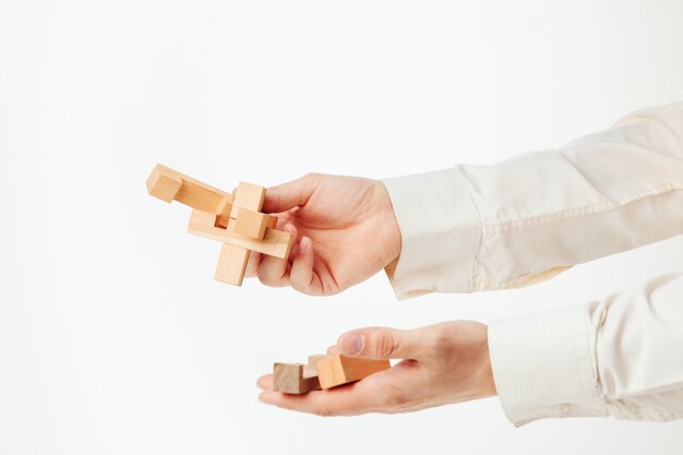 The toy wooden puzzle in hands solated on white background