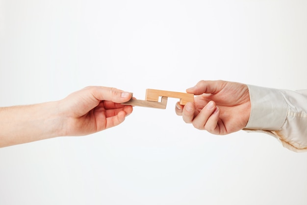 The toy wooden puzzle in hands solated on white background