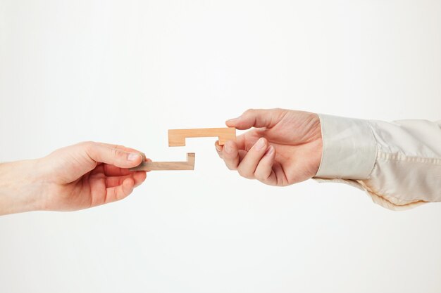 The toy wooden puzzle in hands solated on white background