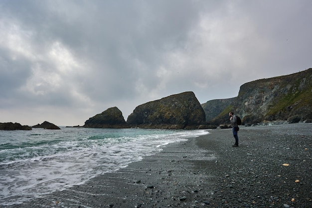 아일랜드의 tra na mbo 해변. 절벽으로 둘러싸인 멋진 해변에서 수평선을 바라보는 사람