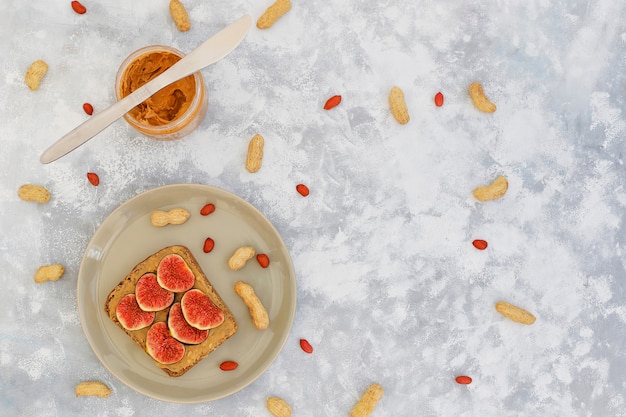 Colazione estiva tradizionale americana ed europea: toast con burro d'arachidi, bacche, pesca, fichi, fragole, lamponi, copia vista dall'alto