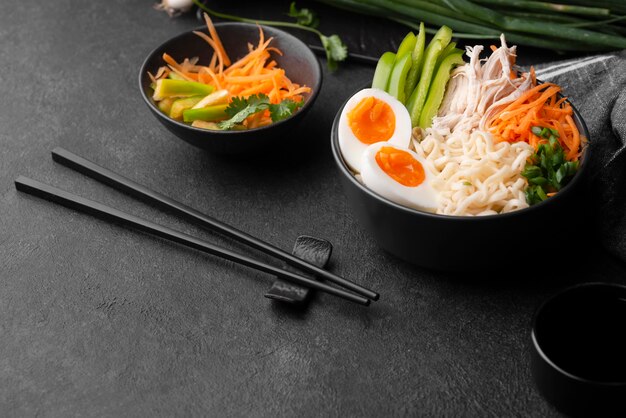 Traditional asian noodles with eggs, vegetables and chopsticks