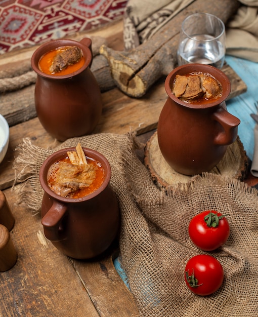 Traditional Azerbaijani meal piti in pottery cups served with tomatoes.