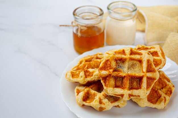 Traditional Belgian waffles, blood oranges and blueberries dressing and cup of coffee for sweet breakfast, composition on light background.