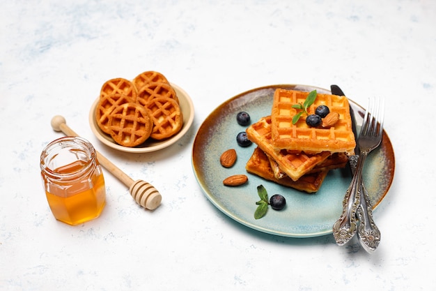 Traditional belgian waffles with fresh berries and honey on grey concrete surface. 