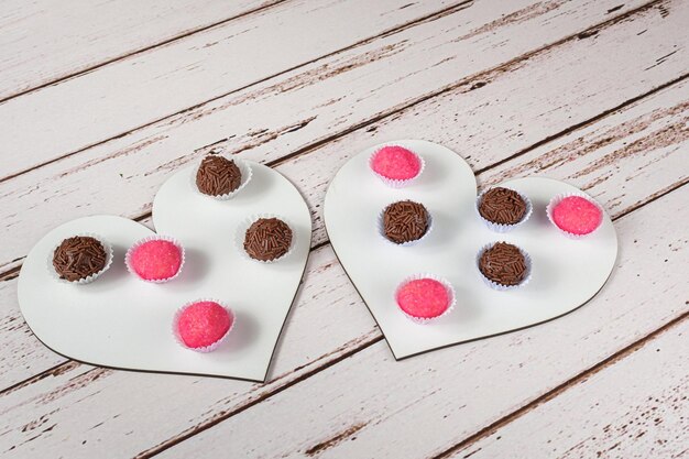 Traditional brigadeiros and animals standing on two heart shaped plates. brazilian sweets.