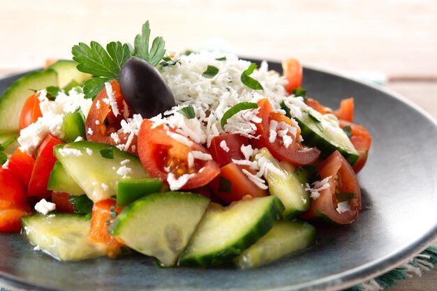 Traditional Bulgarian shopska salad with tomatocucumber and bulgarian sirene cheese on wooden table