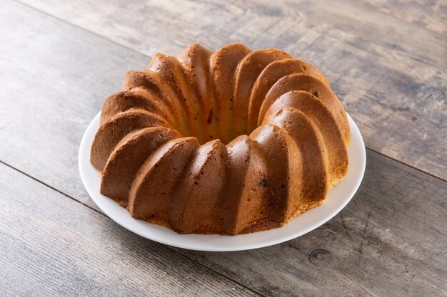 Traditional bundt cake piece with raisins on wooden table