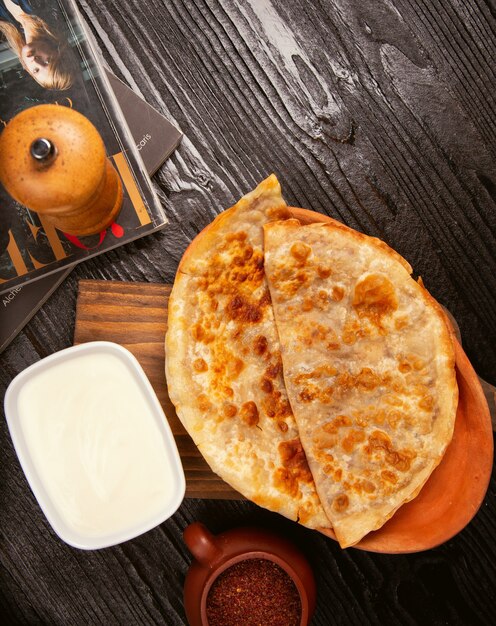 Traditional caucasian gutab, kutab, gozleme with sumakh and yogurt in wooden plate. 