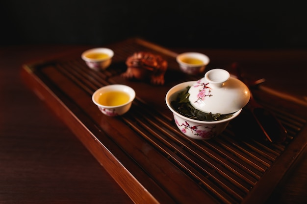 Free photo the traditional chinese tea ceremony. porcelain gaiwan and three cups on a tea desk chaban
