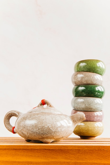 Free photo traditional chinese teapot with stacked of teacups on wooden table