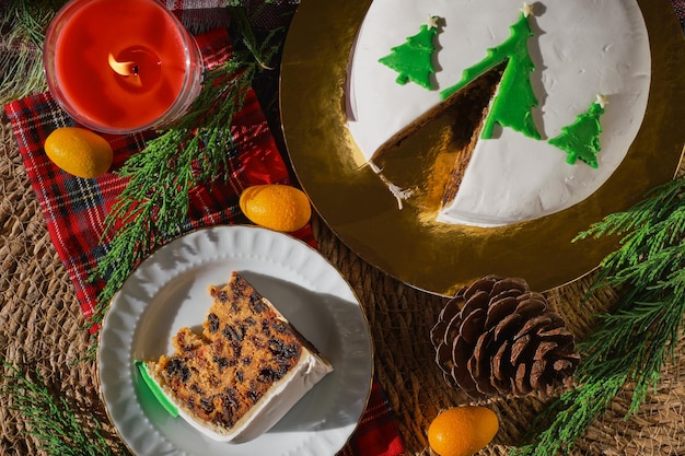 Tradizionale torta di natale o budino sullo sfondo delle decorazioni natalizie vista dall'alto di una fetta di torta su un piatto still life di cibo natalizio con frutta torta inglese con marzapane