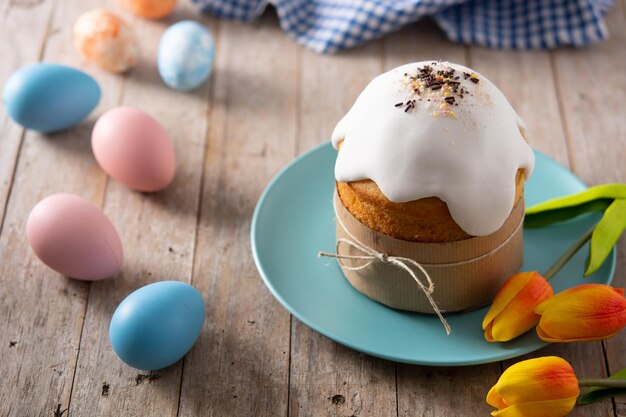 Traditional Easter cake, colorful eggs and tulips on wooden table