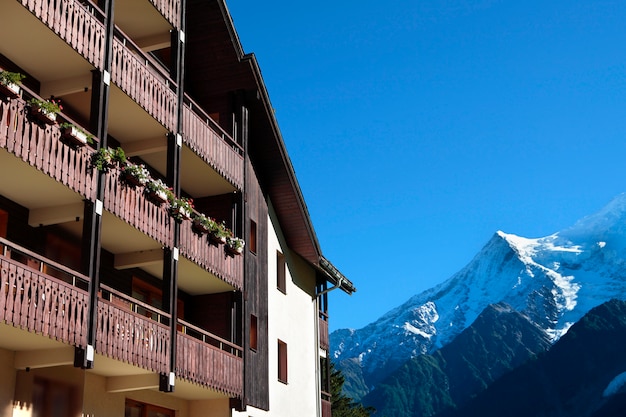 전통적인 유럽 알파인 스키 샬레 호텔, 거리에서 알프스의 전망. 푸른 하늘에 공간을 복사합니다.
