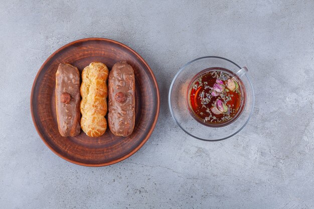 Traditional french eclairs with chocolate and a glass cup of tea. 