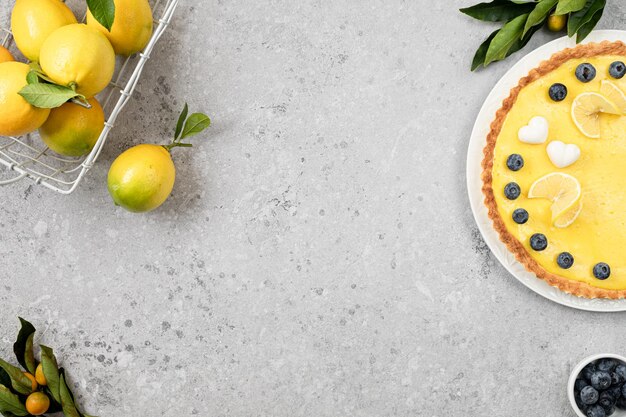 Traditional French lemon pie with blueberries on a white stone background