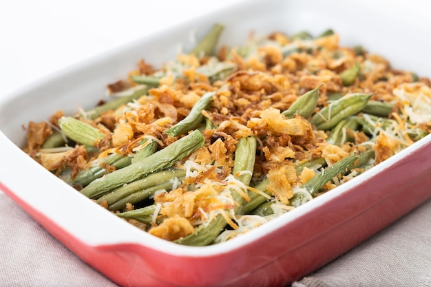 A traditional green bean casserole topped with French Fried Onions and cream of mushroom isolated on white background Copy space