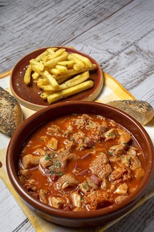 Традиционный домашний и типичный рецепт callos a la madrilã±a с хлебом и картофелем фри. концепция испанской кухни