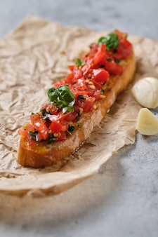 Traditional italian bruschetta with tomato, oregano, olive oil and basil. the process of preparing snacks.