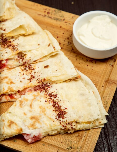 Traditional meat vegetable gutab, qutab, gozleme on wooden board with sumakh, yogurt 