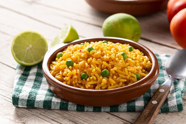 Traditional Mexican rice served with green peas on wooden table