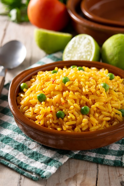 Traditional Mexican rice served with green peas on wooden table