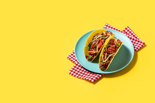 Traditional Mexican tacos with meat and vegetables on yellow background