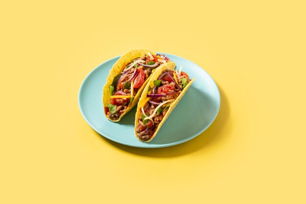 Traditional Mexican tacos with meat and vegetables on yellow background