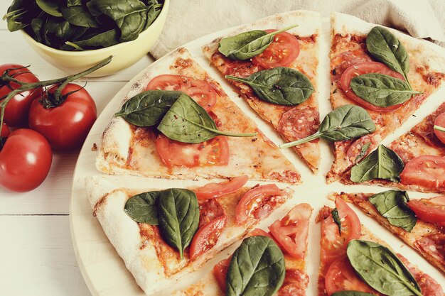 Traditional pizza with tomato slices and basil leaves