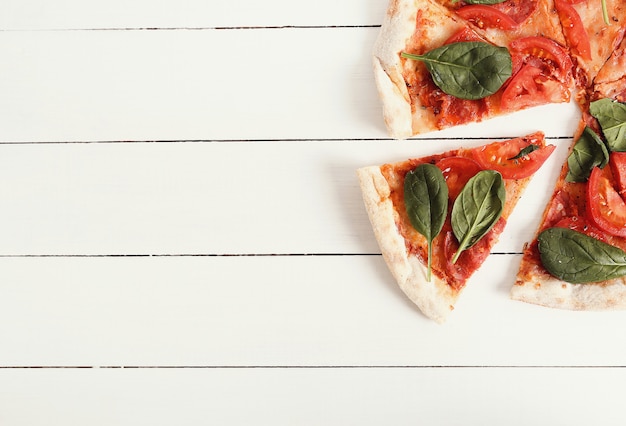 Traditional pizza with tomato slices and basil leaves